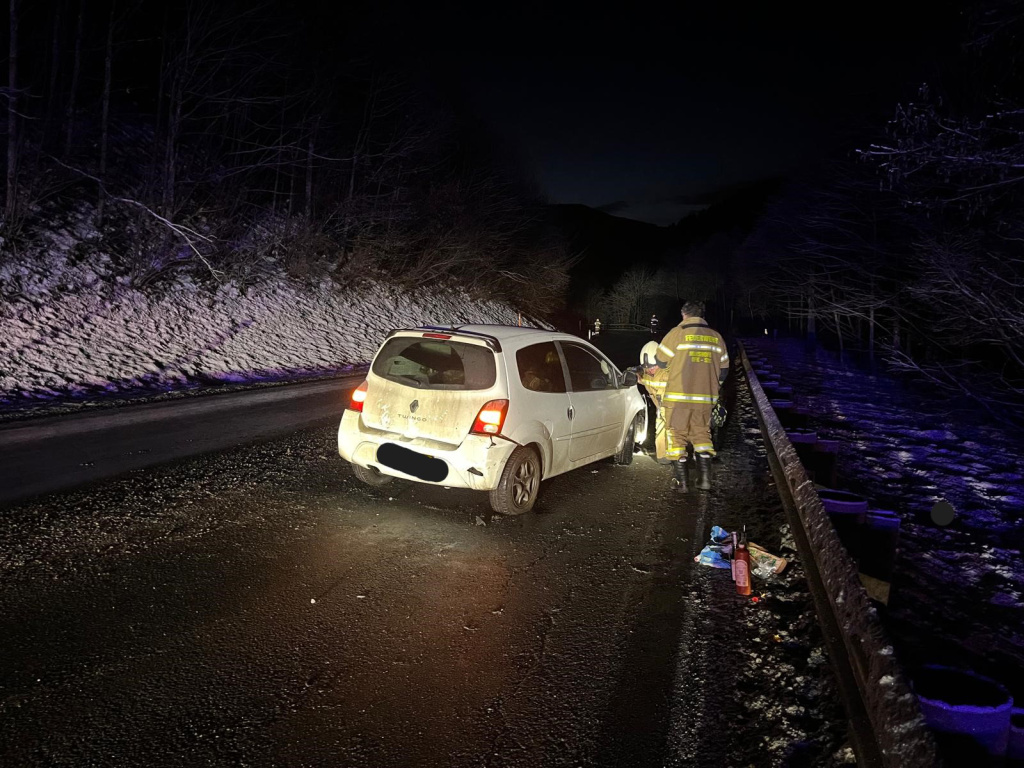 Nächtlicher Verkehrsunfall: beschädigter Pkw am Straßenrand, Feuerwehr sichert Unfallstelle