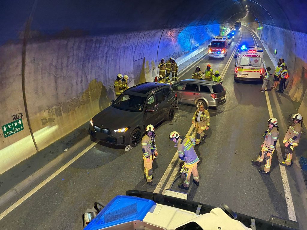Feuerwehrkräfte sichern Unfallstelle mit zwei Pkw und Rettungswagen in einem Straßentunnel
